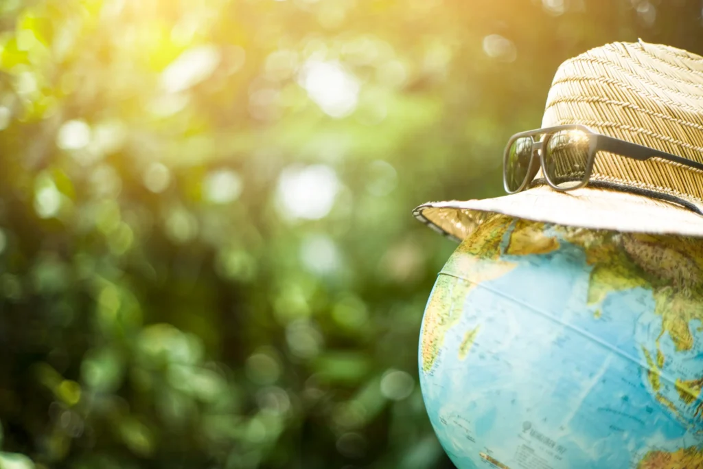 Globe wearing a hat and sunglasses symbolizing sustainable and eco-friendly travel around the world.