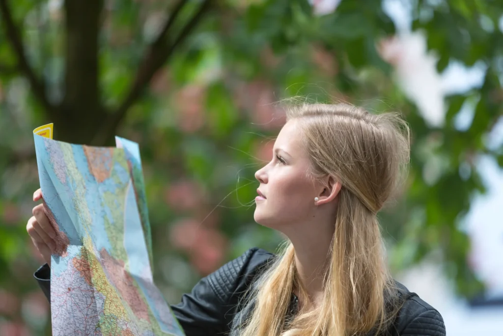 Young traveler reading a map outdoors, planning an eco-conscious journey through Europe.