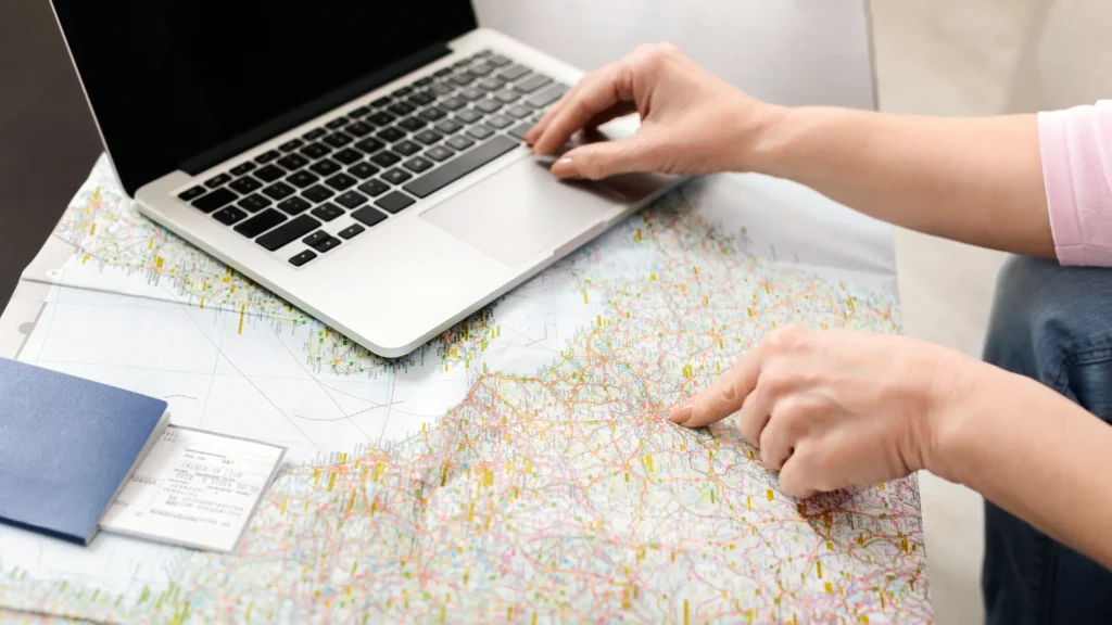 Woman using a laptop and map to plan a trip — symbolizing local SEO and travel planning for hotels and tour operators