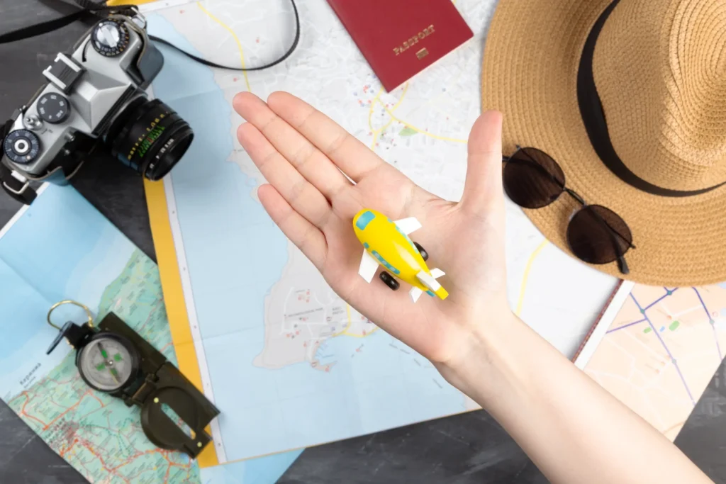 Travel planning essentials with a hand holding a toy airplane, symbolizing travel agency branding.