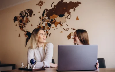 Two travel consultants discussing trip plans on a laptop in a relaxed setting.